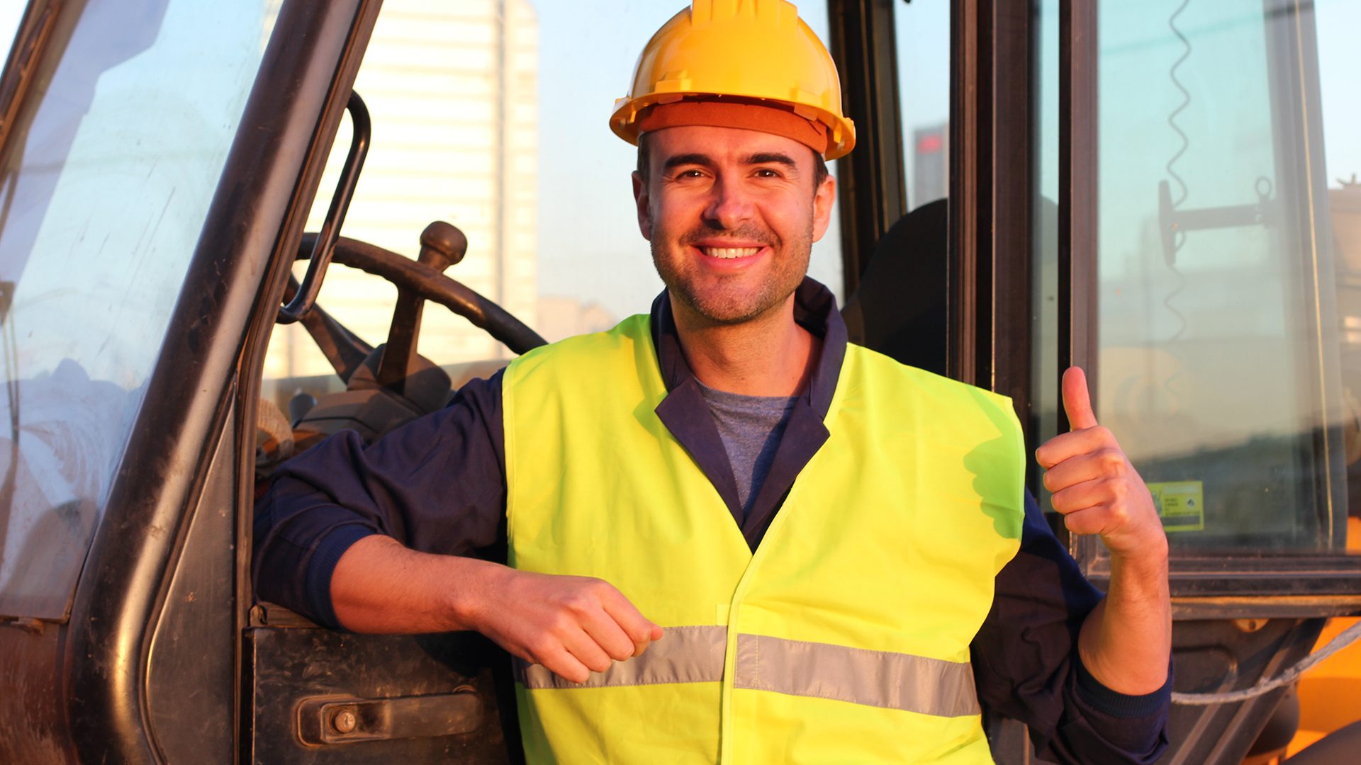 Closeup of a man in a safety vest smiling and giving a thumbs up