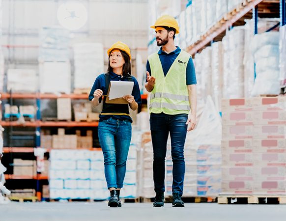 Two workers in safety gear inspect a warehouse
